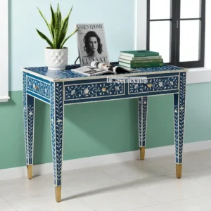 Handcrafted Floral Bone Inlay Console Table in Deep Blue and White with Gold-Tipped Legs – Decorated with books, a plant, and a magazine in a bright modern room near a window.